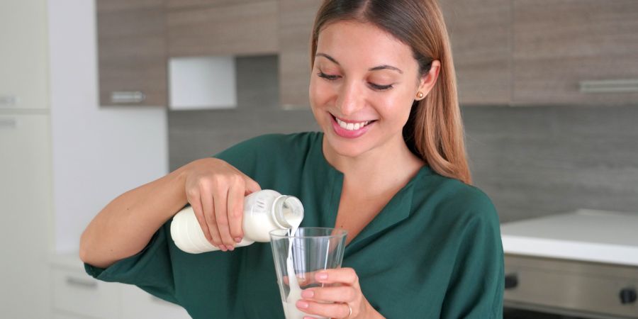 Junge Frau schenkt Milchgetränk ein