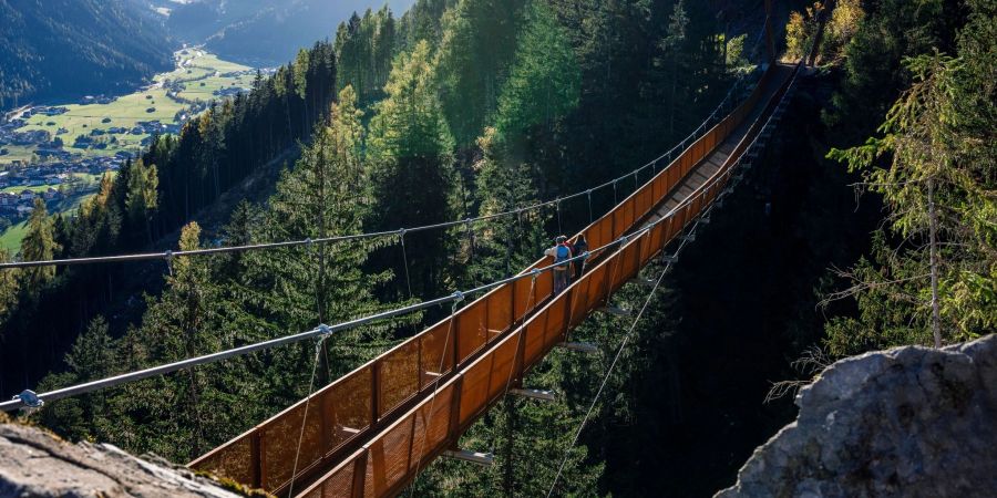 Wandern mit Aussicht: Die mehr als 100 Meter lange Hängebrücke im Stubaital führt an einem Berghang 46 Meter über den Boden und eröffnet einen Fernblick auf den Ort Neustift.