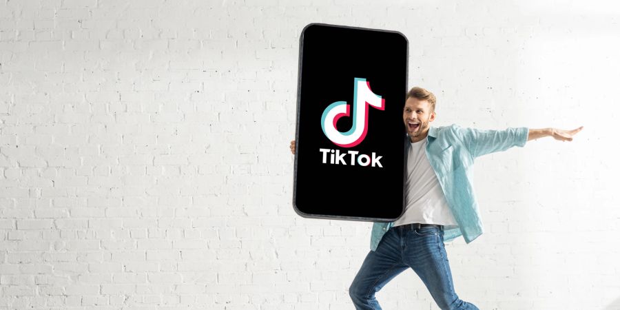 Mann mit überdimensioniertem Smartphone inkl. TikTok-App