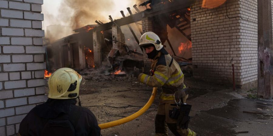 dpatopbilder - Rettungskräfte löschen ein Feuer in einer Autowerkstatt, die durch einen russischen Angriff beschädigt wurde. Foto: Evgeniy Maloletka/AP/dpa