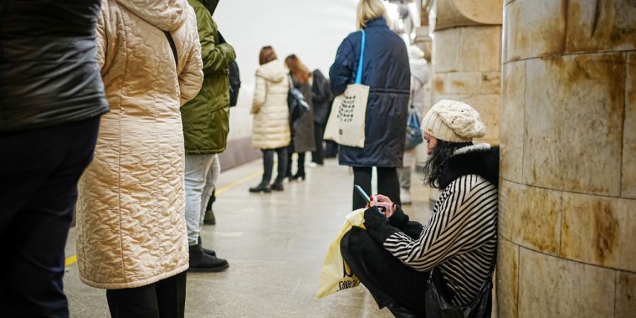 ARCHIV - Passanten stehen und hocken während eines Luftalarms in der Metro in der ukrainischen Hauptstadt Kiew. Am 24.02.2023 jährt sich der russische Angriffskrieg auf die Ukraine da...