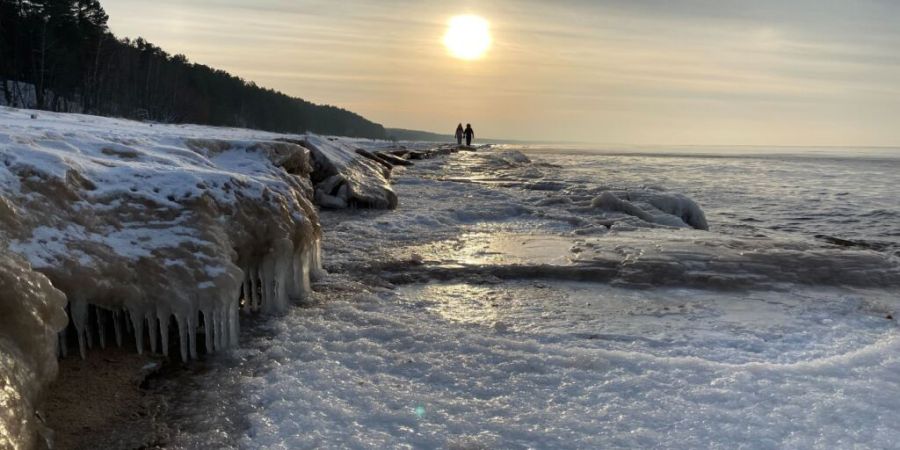 ARCHIV - Spaziergänger gehen am Strand der teilweise zugefrorenen Ostsee entlang. Foto: Alexander Welscher/dpa