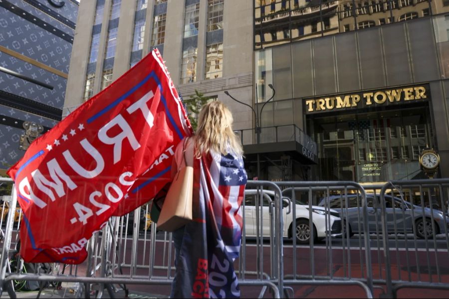 Eine Trump-Anhängerin schwenkt eine rote Trump-Flagge vor dem Trump-Tower in New York.