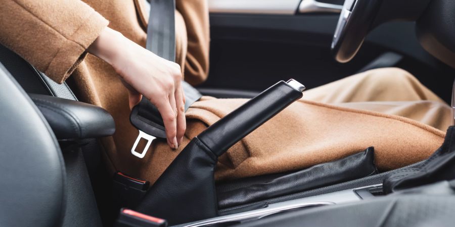 Frau im Auto schnallt sich an.