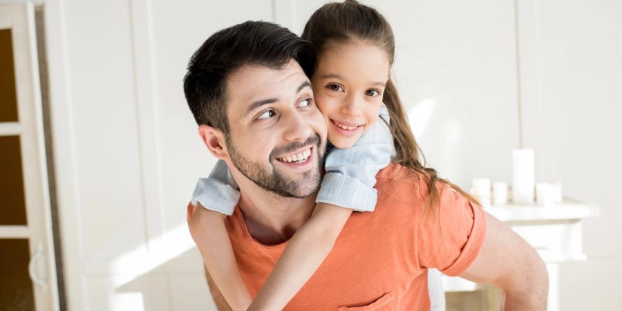 Vater trägt Tochter auf dem Rücken