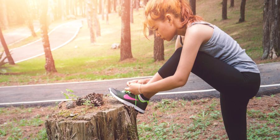 Sportliche Frau bindet Laufschuhe