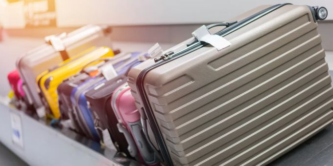 Bunt gemischte Koffer auf dem Gepäckband – doch nicht jede Farbe ist gleich clever gewählt. Koffer Flughafen