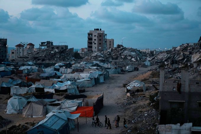 Palästinenser, die durch die israelische Luft- und Bodenoffensive auf den Gazastreifen vertrieben wurden, gehen in der Abenddämmerung über einen Platz in einem behelfsmässigen Zeltlager. Gaza