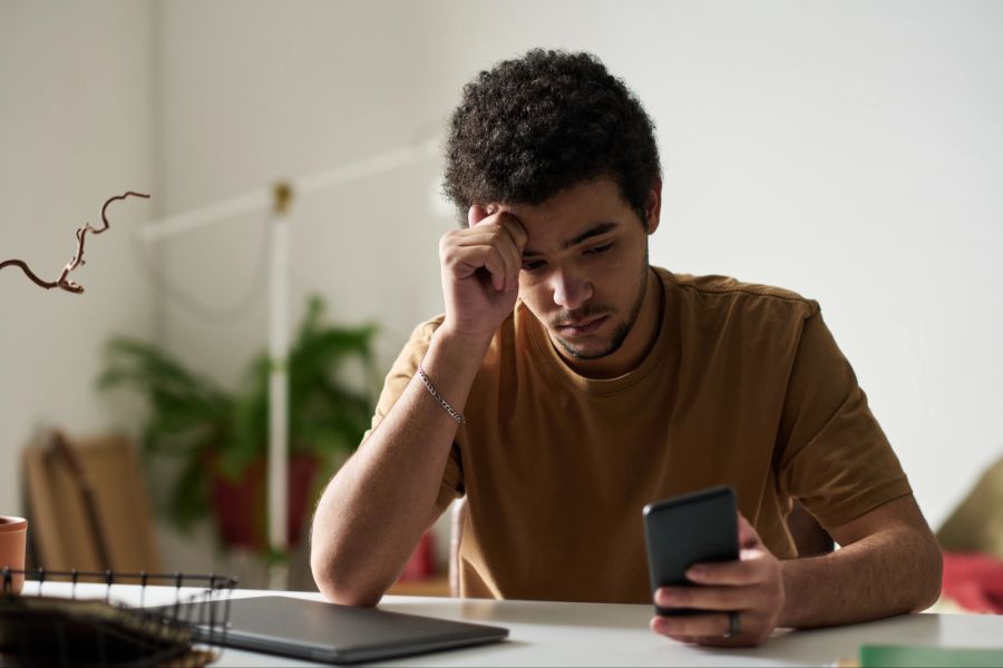 Trauriger Mann schaut aufs Smartphone