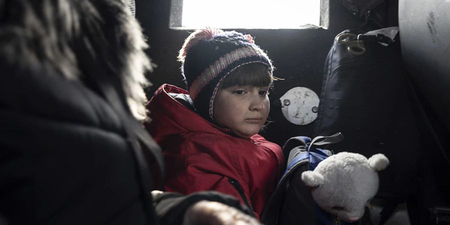 ARCHIV - Dieses von der Nachrichtenagentur AP am 21.03.2023 zur Verfügung gestellte Foto zeigt ein Mädchen, das mit seiner Mutter während der Evakuierung in einem Fahrzeug sitzt. Foto: Evgeniy Maloletka/AP/dpa