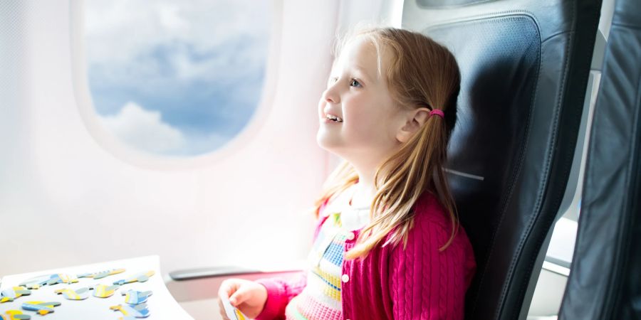 Mädchen puzzelt im Flugzeug.