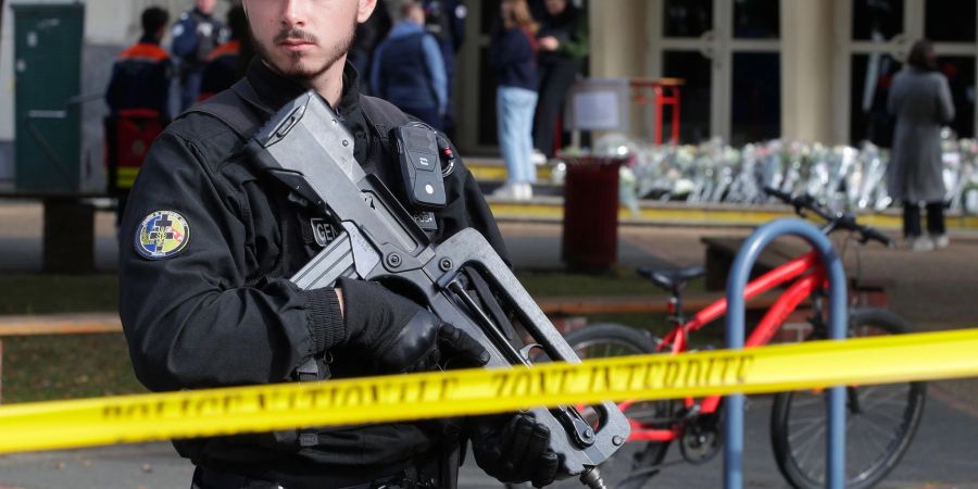 Ein schwer bewaffneter französischer Polizist vor einem Gymnasium (Archivbild). In Frankreich häufen sich seit einigen Tagen Bombendrohungen, insbesondere gegen Schulen - nun gibt es auch welche gegen mehrere Regionalflughäfen.