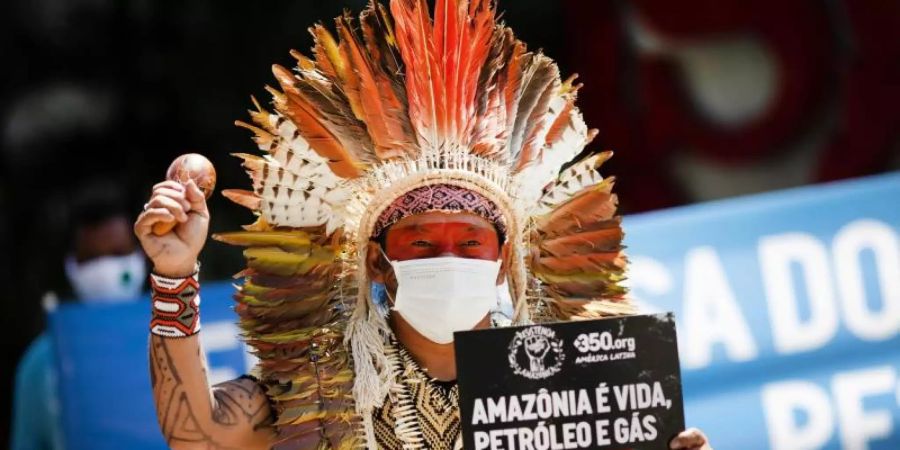 Ninawa Inu Huni kui hält ein Schild mit der Aufschrift «Amazonen ist Leben, Öl und Gas sind Tod» während eines Protests gegen Auktionen zur Erkundung von Ölfeldern in den Amazonen vor einem Hotel in Rio de Janeiro. Foto: Silvia Izquierdo/AP/dpa