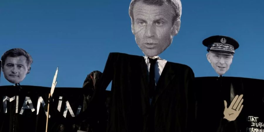Bilder von Macron (Mitte), seinem Innenminister und dem Pariser Polizeichef bei einer Demo