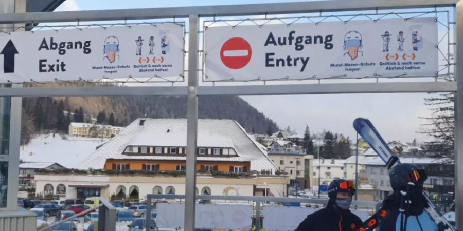 HANDOUT - Skifahrer gehen in Semmering unter Schildern, die auf die coronabedingten Hygieneregeln hinweisen, durch. Foto: Semmering-Hirschenkogel Bergbahn/APA/dpa - ACHTUNG: Nur zur redaktionellen Verwendung und nur mit vollständiger Nennung des vorstehenden Credits