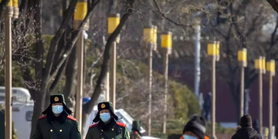 Chinesische paramilitärische Polizisten mit Mund-Nasen-Schutz patrouillieren entlang einer Strasse in Peking. Foto: Mark Schiefelbein/AP/dpa