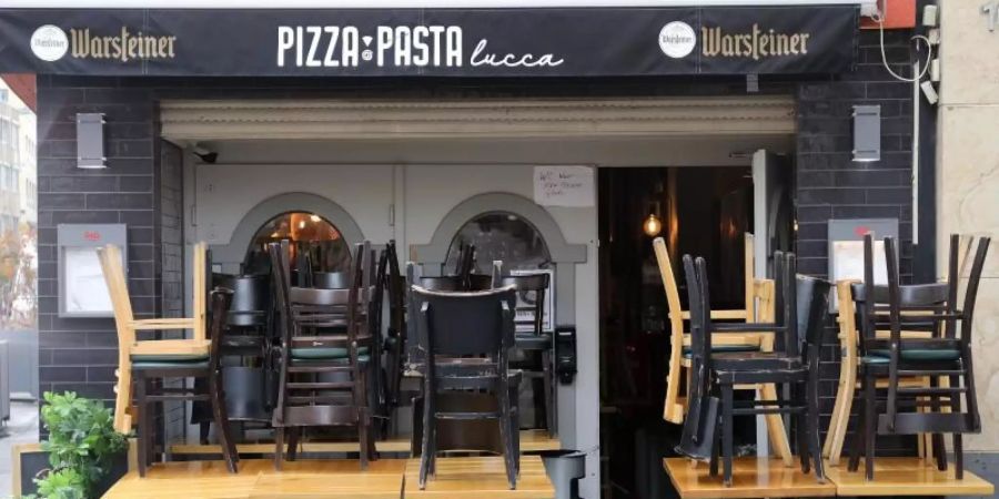 Hier darf man nicht essen: Vor einem Restaurant in Köln stehen die Stühle coronabedingt auf den Tischen. Foto: Oliver Berg/dpa