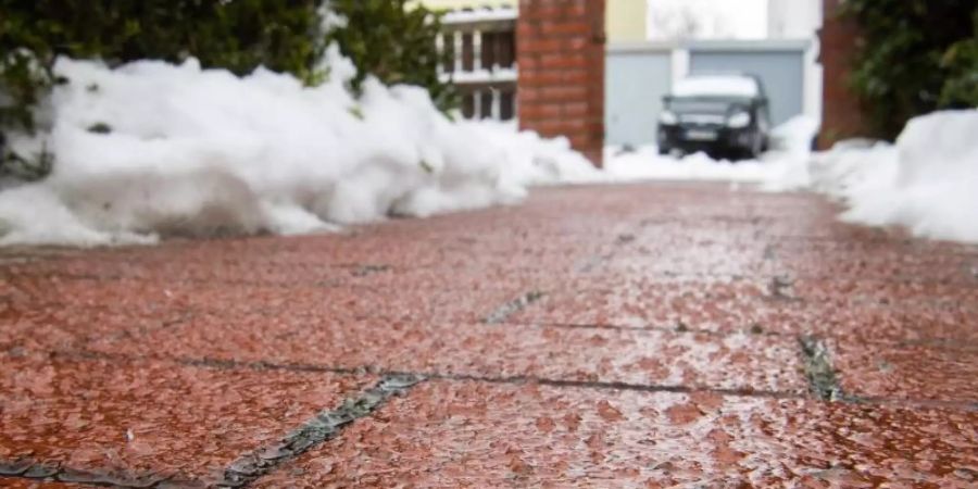 Regen gefriert auf eiskaltem Boden zu einer dünnen Eisschicht. Foto: Julian Stratenschulte/dpa