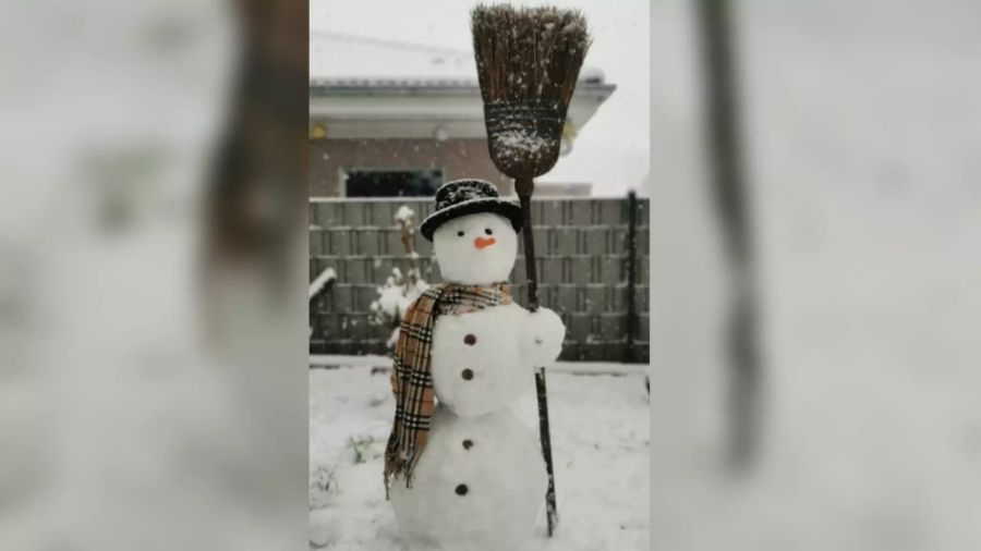 Dieser Schneemann ist mit Besen und Schal ausgerüstet.