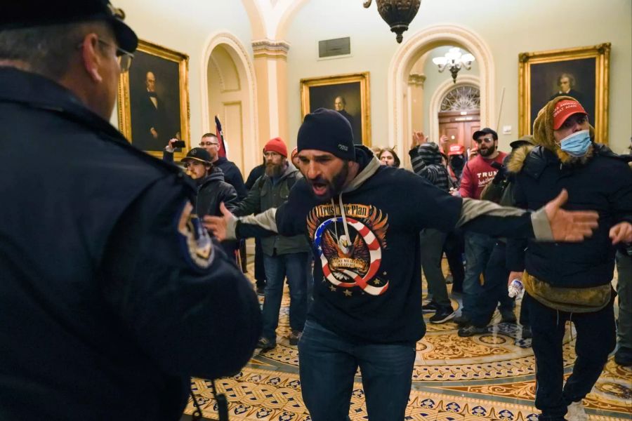 Demonstranten gestikulieren vor der US-Kapitol-Polizei auf dem Gang vor der Senatskammer im Kapitol. Die Polizei war deutlich in der Unterzahl.