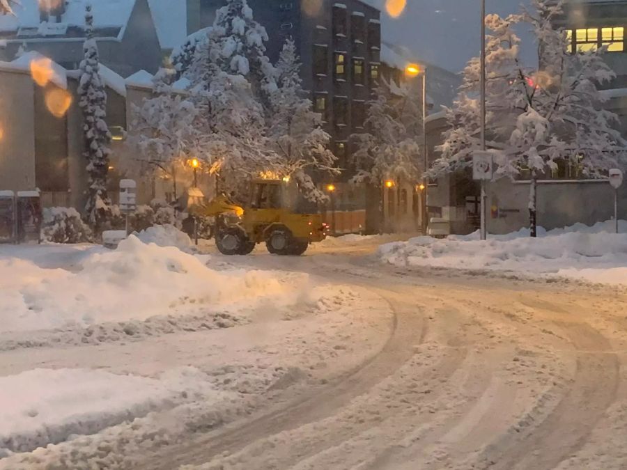 Ein Bagger versucht die Strasse beim Bahnhof in Baden AG vom Schnee zu befreien.