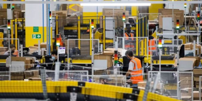 Mitarbeiter mit Mund-Nasen-Bedeckung in einem Logistikzentrum des Versandhändlers Amazon in Mönchengladbach. Foto: Rolf Vennenbernd/dpa Mitarbeiter mit Mund-Nasen-Bedeckung in einem Logistikzentrum des Versandhändlers Amazon in Mönchengladbach. Foto: Rolf Vennenbernd/dpa
