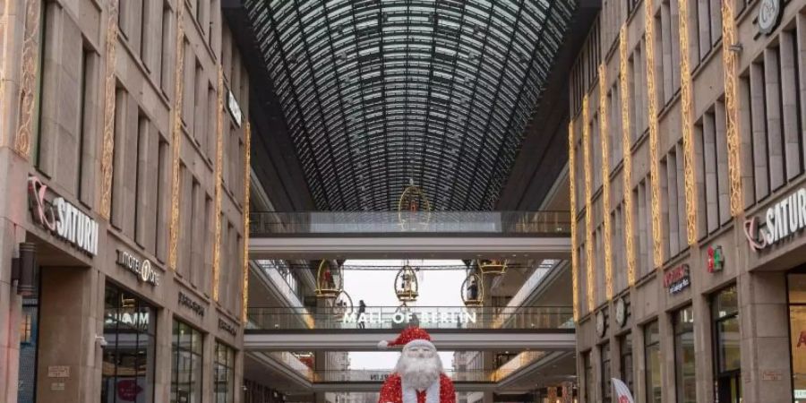 Vor dem Einkaufszentrum «Mall of Berlin» steht eine Weihnachtsmann-Skulptur. Der Teil-Lockdown dämpft die Konsumlaune empfindlich. Foto: Christophe Gateau/dpa