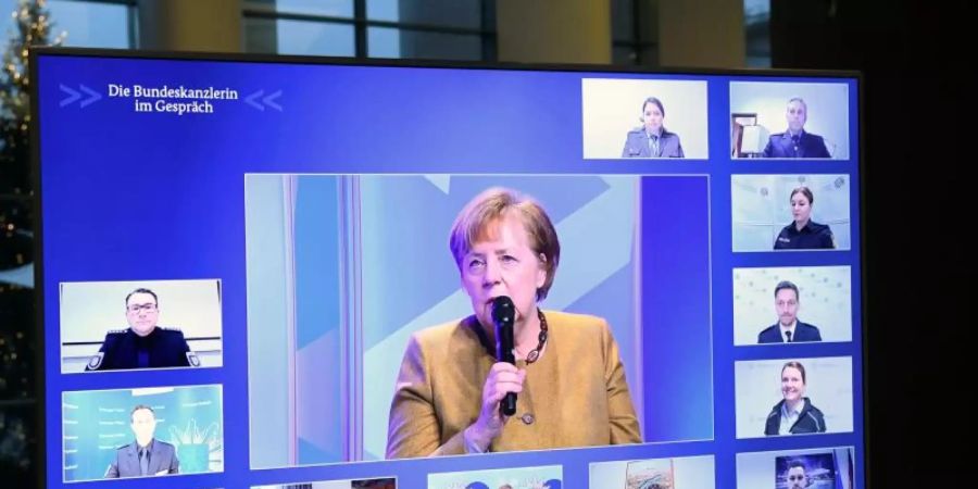 Kanzlerin Angela Merkel spricht mit Polizeibeamten und Polizeibeamtinnen. Foto: Annegret Hilse/Reuters Images Europe/Pool/dpa