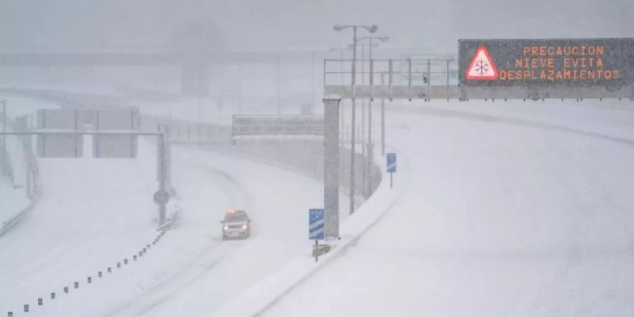 Ein Rettungsfahrzeug fährt auf der leeren, schneebedeckten Schnellstrasse M-30 durch Madrid. Foto: Meng Dingbo/XinHua/dpa