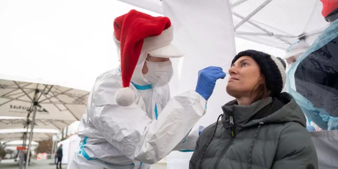Eine ehrenamtliche DRK-Helferin, die eine Bommelmütze an hat, führt in einer Teststation einen Corona-Schnelltest an einer Frau durch. Deutchland corona test
