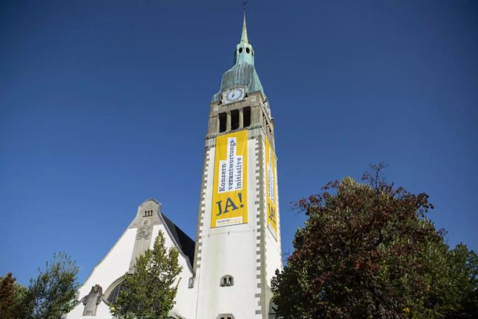 Übergrosse Banner zur Konzern-Initiative an der reformierten Pauluskirche in Bern. Ja Konzern-Initiative Banner an Kirche in Bern.
