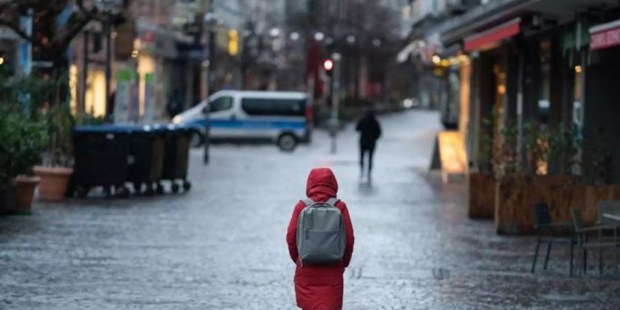Eine Frau geht durch die nahezu menschenleere Innenstadt von Frankfurt am Main. Foto: Frank Rumpenhorst/dpa