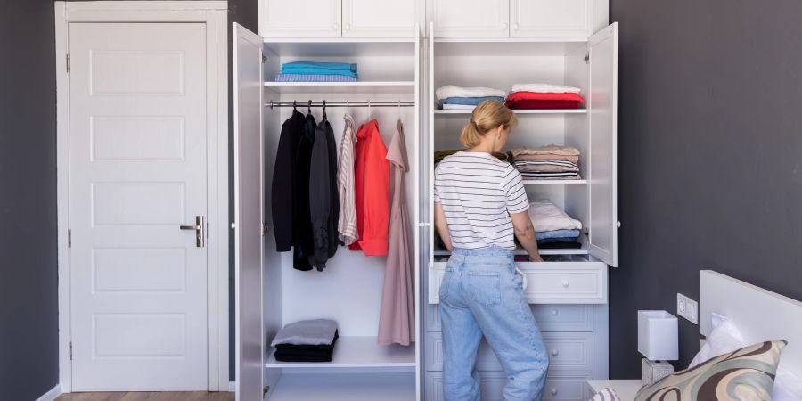 Junge Frau sortiert Kleiderschrank aus