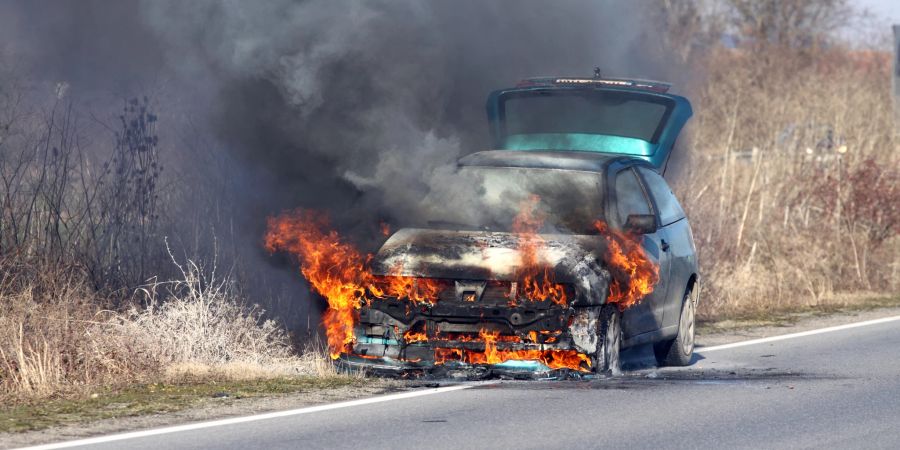 Brennendes Auto am Straßenrand