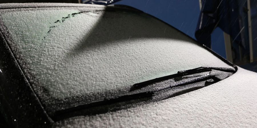 Schnee liegt auf der Windschutzscheibe eines Autos am Flughafen Hamburg.