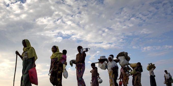 Flüchtlinge der Rohingya gehen mit ihrem Gepäck über ein Reisfeld in Bangladesch. rohingya