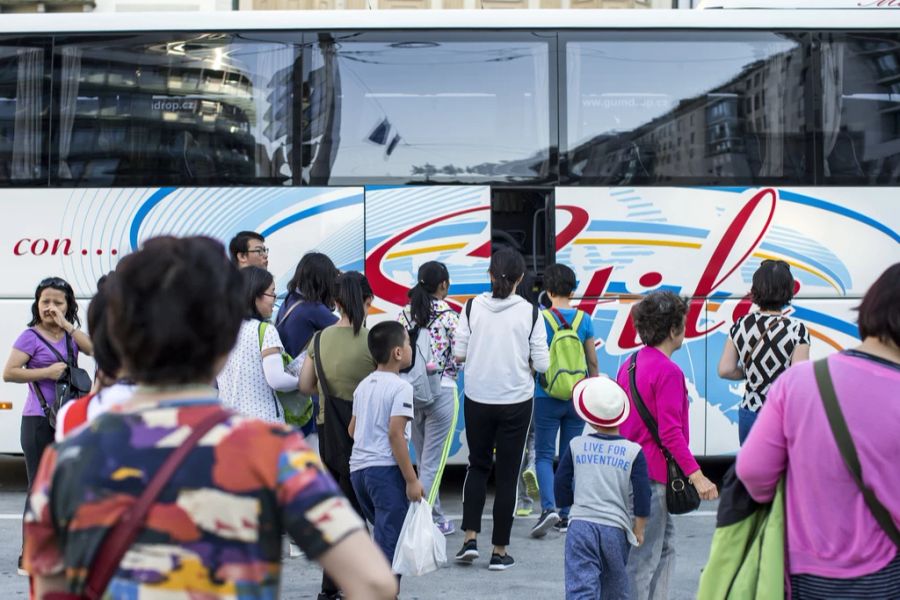 Asiatische Touristen steigen in Luzern in einen Reisebus ein.