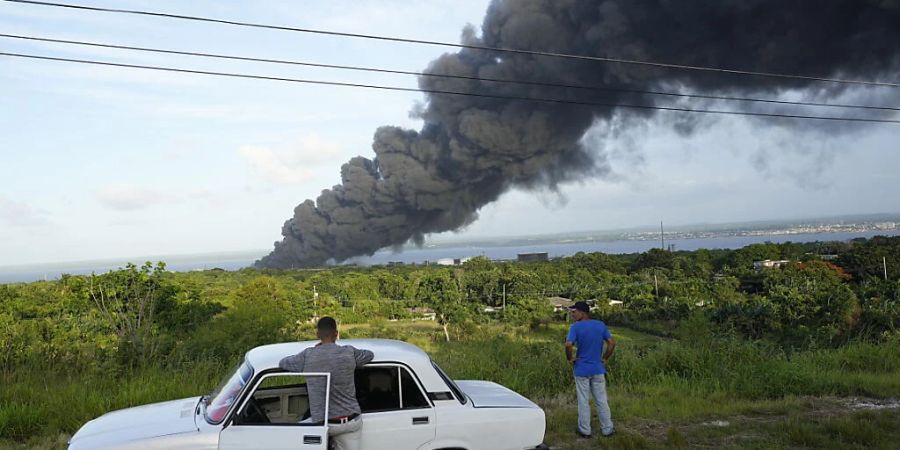 dpatopbilder - Menschen beobachten eine riesige aufsteigende Rauchwolke aus der Matanzas Supertanker-Basis. Foto: Ramon Espinosa/AP/dpa