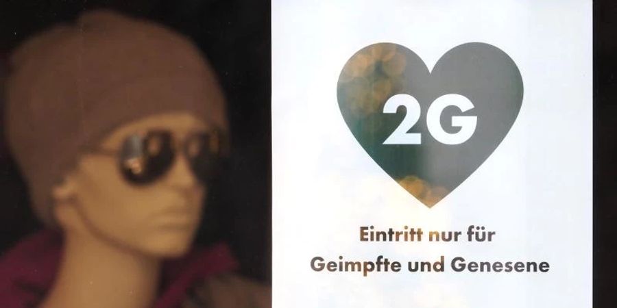 Ein Schild mit der Aufschrift «2G - Eintritt nur für Geimpfte und Genesene» hängt im Schaufenster eines Modegeschäftes in Potsdam. Foto: Soeren Stache/dpa-Zentralbild/dpa
