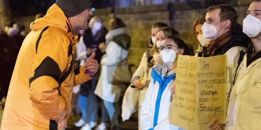 Ein Teilnehmer einer als «Spaziergang» deklarierten Demo von Impfgegnern und Kritikern der Corona-Massnahmen redet am Uni-Klinikum Dresden auf zahlreiche Gegendemonstranten ein. Foto: Sebastian Kahnert/dpa-Zentralbild/dpa