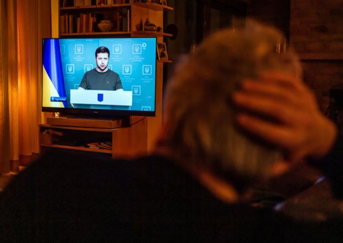 Ein Mann hört in der Ukraine einer Fernsehansprache von Wolodymyr Selenskyj zu. Ukraine-Krieg