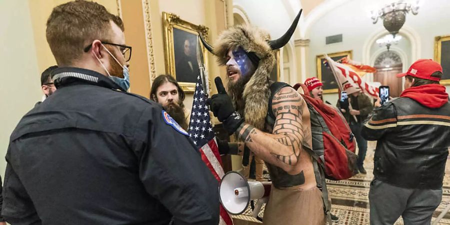 ARCHIV - Ein Unterstützer von US-Präsident Trump diskutiert auf dem Gang vor der Senatskammer im US-Kapitol mit einem Polizisten. Foto: Manuel Balce Ceneta/AP/dpa