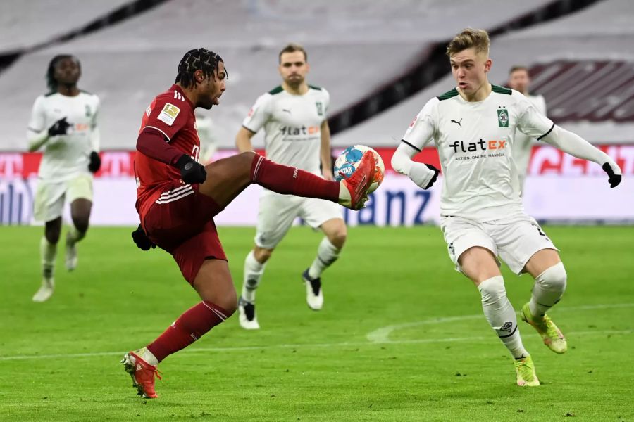 Bayerns Serge Gnabry (l.) kontrolliert den Ball vor den Augen von Luca Netz (r.)