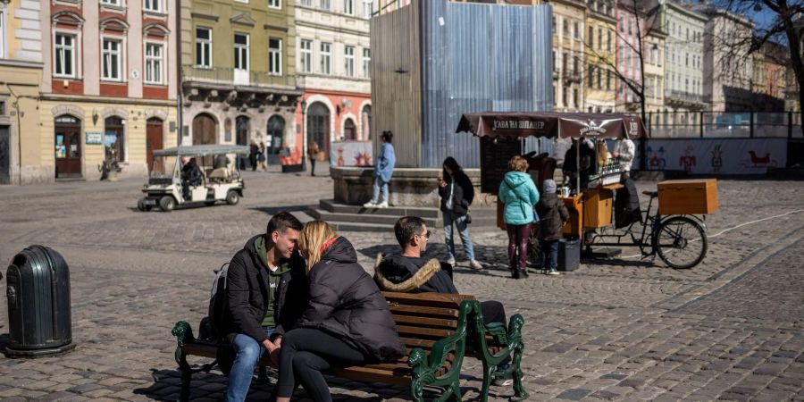 Ein küssendes Paar sitzt in der Innenstadt von Lwiw auf einer Bank.