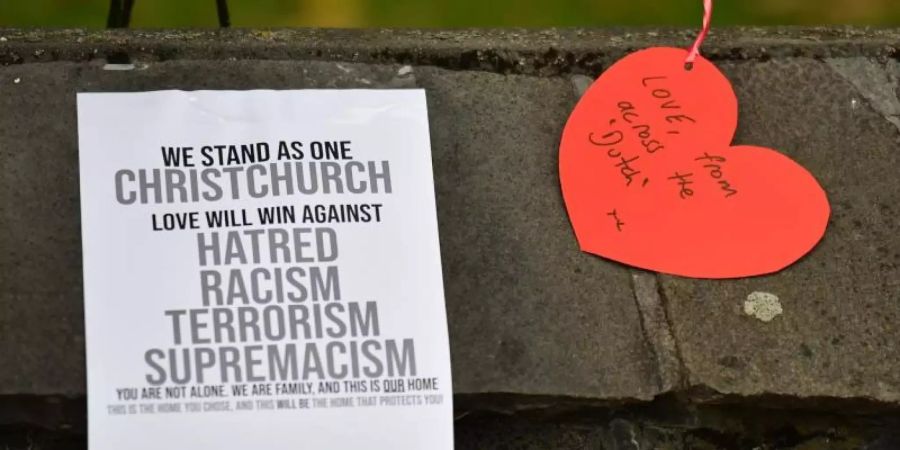 Ein Poster gegen Rassismus ist auf einer Mauer an einem provisorischen Denkmal für die Opfer im Botanischen Garten von Christchurch zu sehen. Foto: Mick Tsikas/AAP