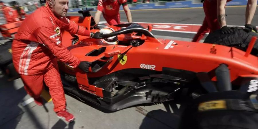 Die Boxencrew von Ferrari schiebt den Rennwagen von Sebastian Vettel in die Boxengasse. Foto: Rick Rycroft/AP