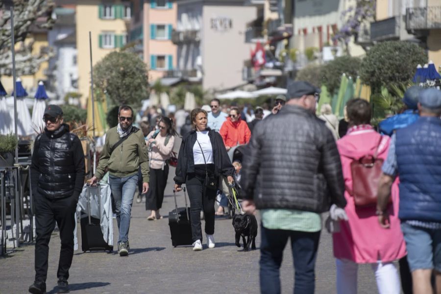 Menschen spazieren in Ascona die Seepromenade entlang.