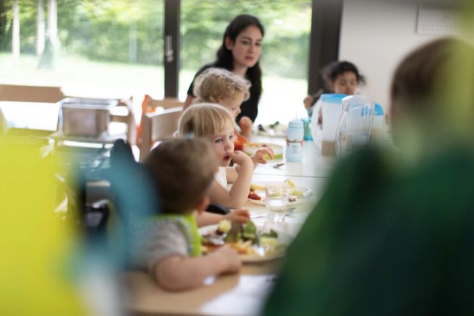 Kinder und Betreuungspersonal einer Kita beim gemeinsamen Mittagessen. Die Verfügbarkeit von qualitativ guten und bezahlbaren Kinderbetreuungsangeboten müsse verbessert werden. (Symbolbild) Kinderbetreuungsangebote Lohnungleichheit