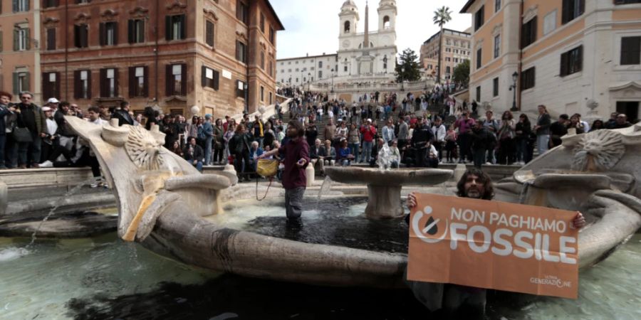 Umweltaktivisten protestieren im Brunnen «Fontana della Barcaccia» (Bootsbrunnen) vor der Spanischen Treppe auf der Piazza di Spagna. Auf dem Plakat steht: «Wir zahlen nicht für fossile Brennstoffe» Foto: Cecilia Fabiano/LaPresse/AP/dpa