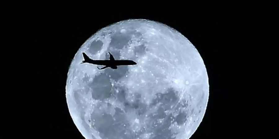 Silhouette eines Flugzeugs vor dem Mond